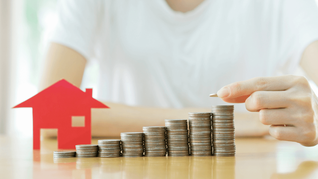 家の模型に硬貨を積む人